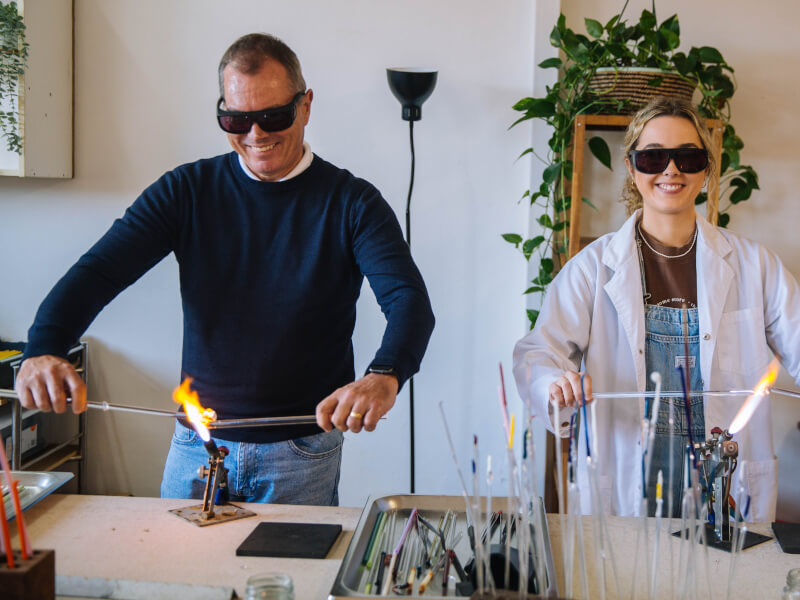 Young woman and man in protective glasses at a glassblowing workshop